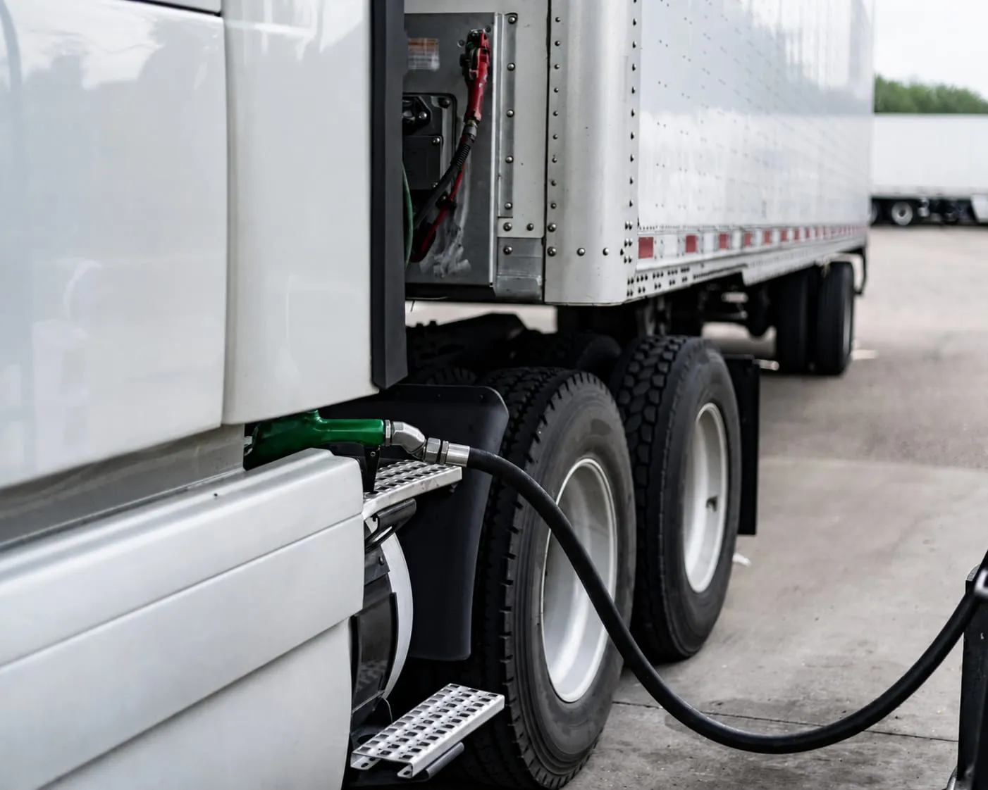 Diesel nozzle fueling a white semi-truck at a truck stop